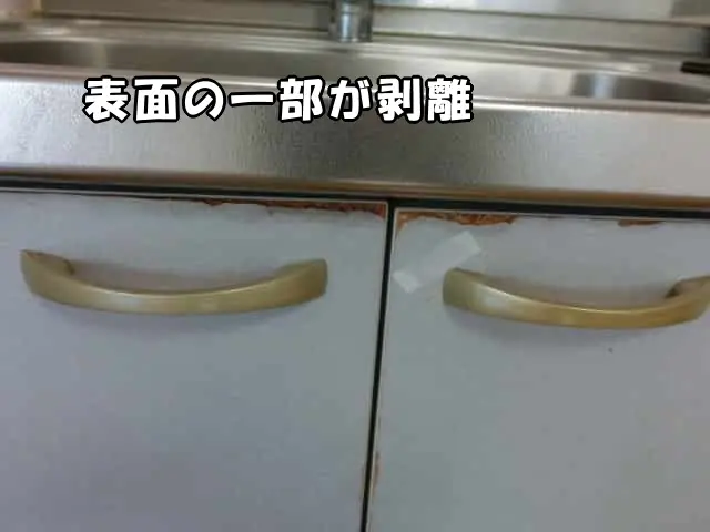 流し台の収納扉上部が傷んで表面の一部が剥離している状態